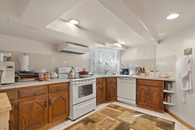 kitchen with white appliances, under cabinet range hood, brown cabinetry, and light tile patterned flooring