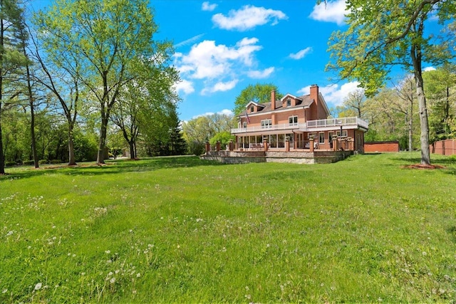 rear view of property with a chimney, a lawn, and a wooden deck