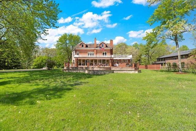 back of property featuring a lawn, a chimney, a wooden deck, and fence