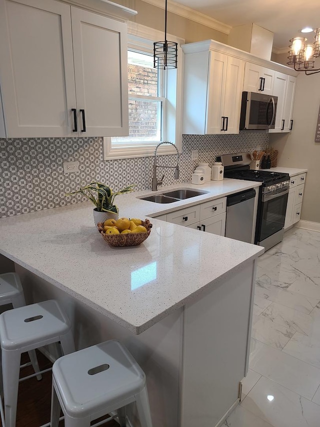 kitchen with appliances with stainless steel finishes, a breakfast bar, sink, decorative light fixtures, and white cabinets