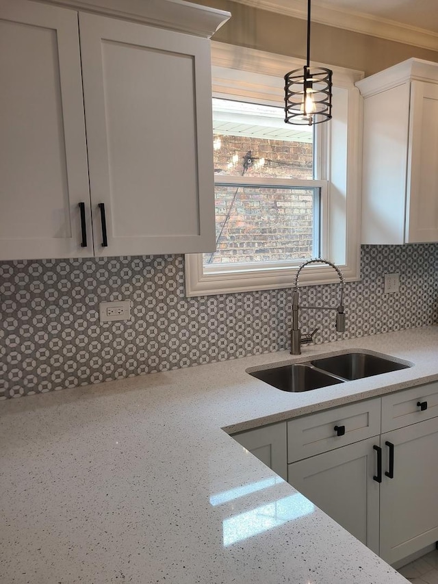 kitchen featuring sink, tasteful backsplash, decorative light fixtures, light stone counters, and white cabinetry