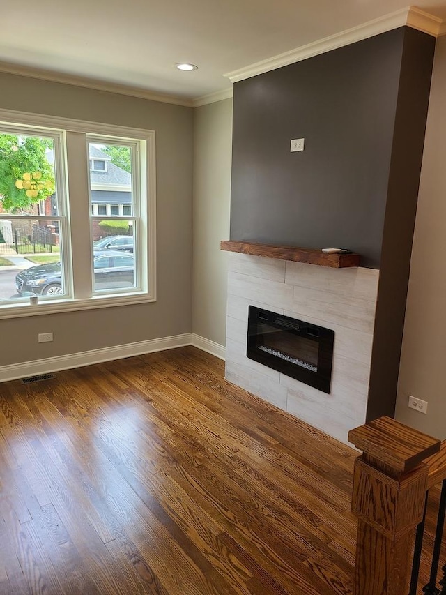 living room with a tiled fireplace, wood-type flooring, and ornamental molding