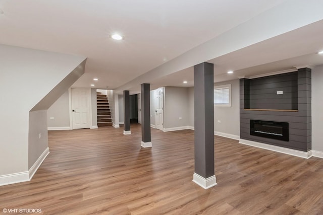 basement featuring a large fireplace and light hardwood / wood-style flooring