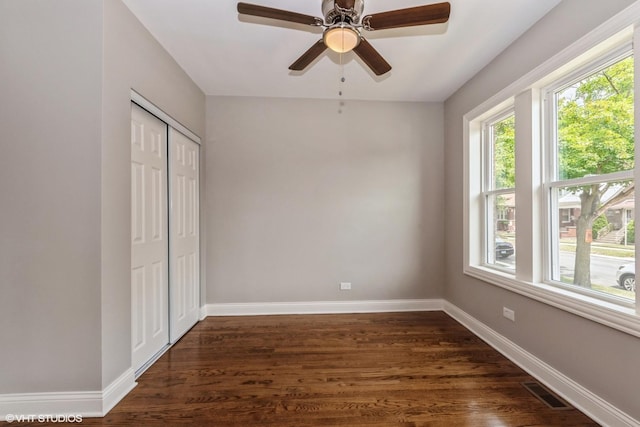 unfurnished bedroom featuring ceiling fan, dark wood-type flooring, and a closet