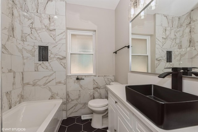 bathroom with tile patterned flooring, toilet, a bathtub, vanity, and tile walls