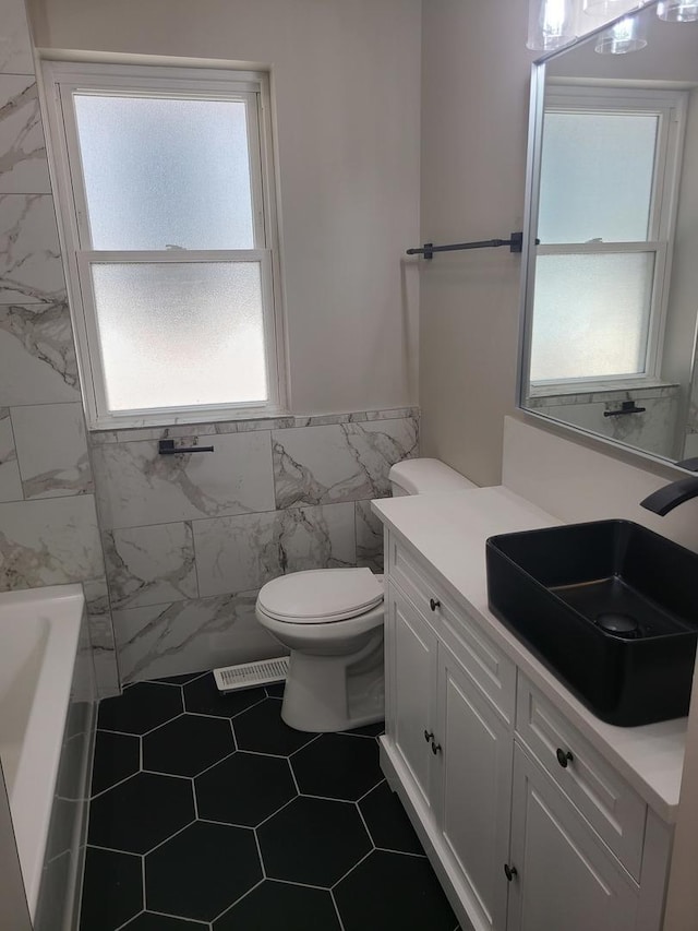 full bathroom with plus walk in shower, tile patterned floors, toilet, vanity, and tile walls