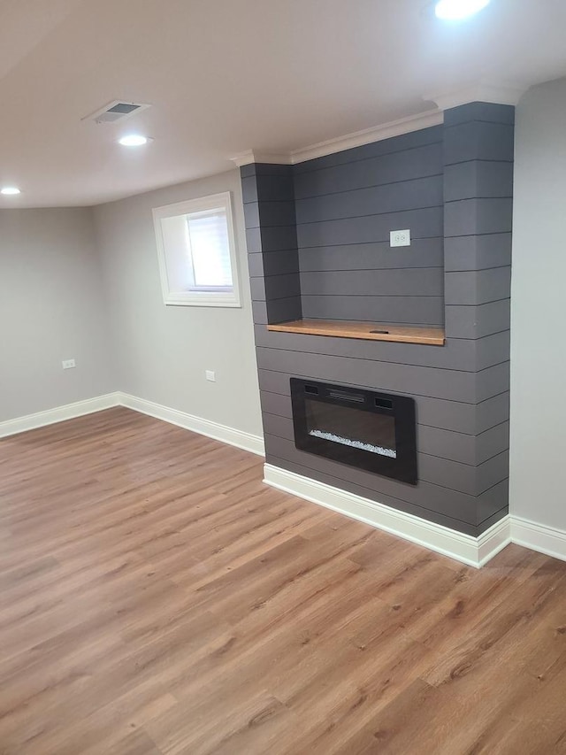 unfurnished living room with a fireplace, light hardwood / wood-style flooring, and ornamental molding