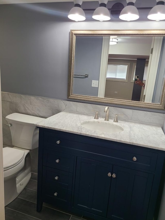 bathroom featuring tile patterned flooring, vanity, tile walls, and toilet