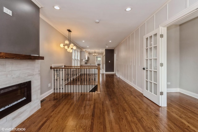 hallway featuring ornamental molding, dark wood-type flooring, and an inviting chandelier