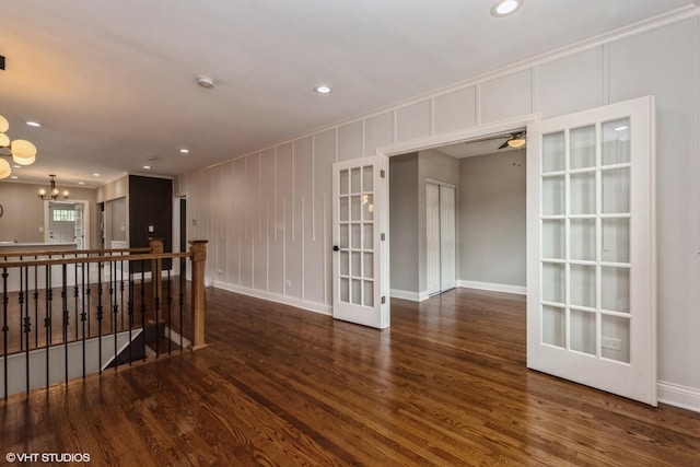 spare room featuring ceiling fan with notable chandelier and dark wood-type flooring