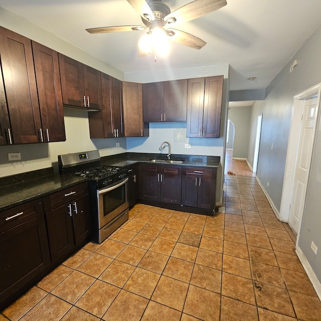 kitchen with sink, dark brown cabinets, stainless steel range with gas stovetop, ceiling fan, and light tile patterned floors