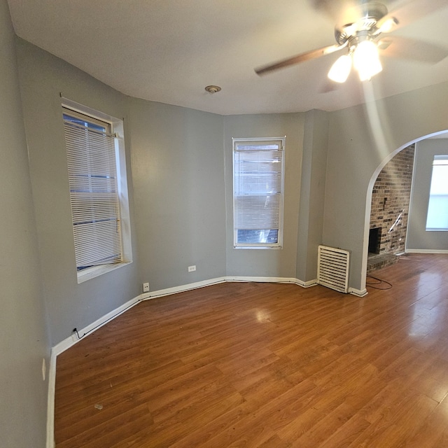 unfurnished living room with ceiling fan, a brick fireplace, and hardwood / wood-style floors