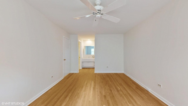 spare room featuring light wood finished floors, a ceiling fan, and baseboards