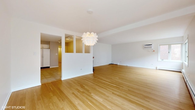 spare room featuring baseboard heating, a baseboard heating unit, wood finished floors, a chandelier, and baseboards