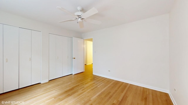 unfurnished bedroom featuring baseboards, light wood-type flooring, a ceiling fan, and multiple closets