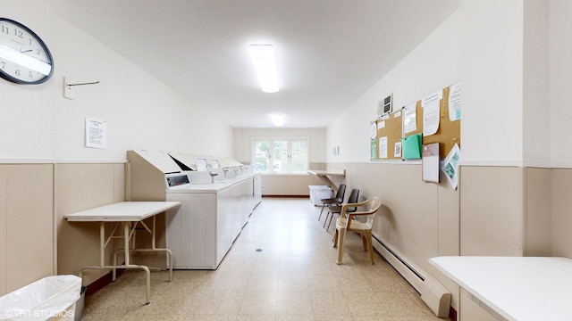 shared laundry area with a wainscoted wall, washer and clothes dryer, light floors, a decorative wall, and a baseboard heating unit