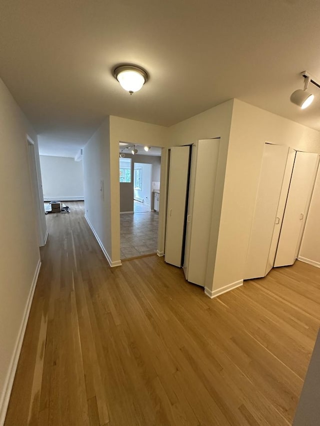 hallway featuring light wood-style floors and baseboards