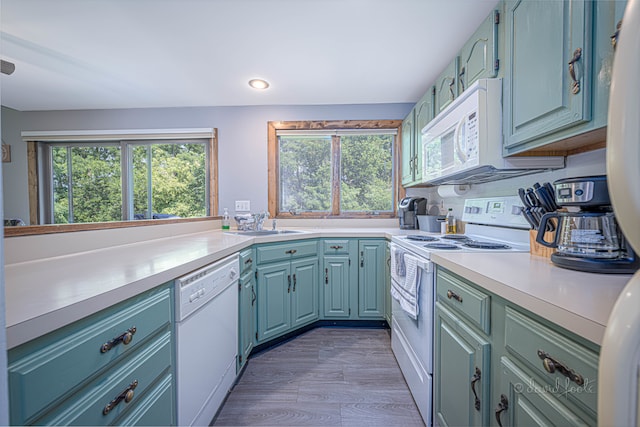 kitchen featuring light wood-type flooring, sink, white appliances, and blue cabinetry