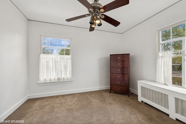 carpeted spare room featuring radiator heating unit and ceiling fan