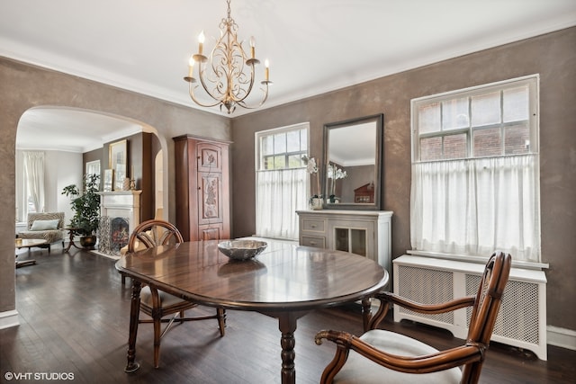 dining space with dark wood-type flooring, ornamental molding, a chandelier, and radiator