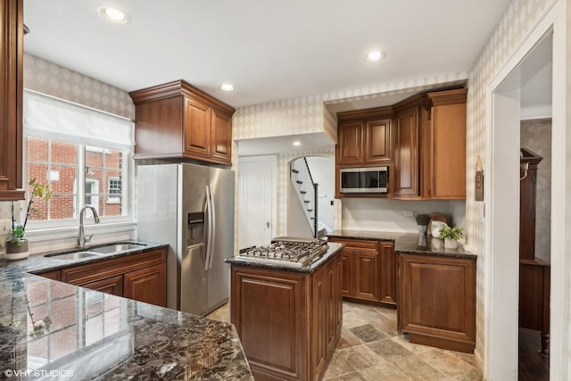 kitchen featuring dark stone counters, light tile patterned flooring, stainless steel appliances, sink, and a kitchen island