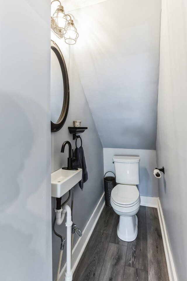 bathroom with lofted ceiling, sink, hardwood / wood-style flooring, and toilet