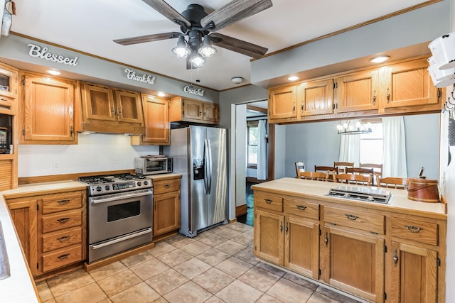 kitchen with ornamental molding, appliances with stainless steel finishes, ceiling fan with notable chandelier, and light tile patterned floors