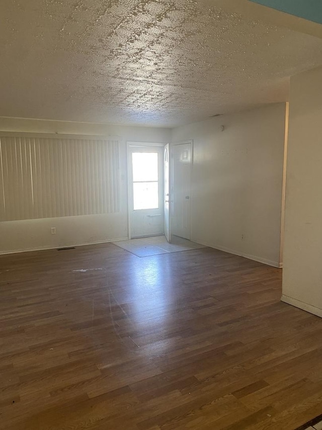 unfurnished room with dark wood-type flooring and a textured ceiling