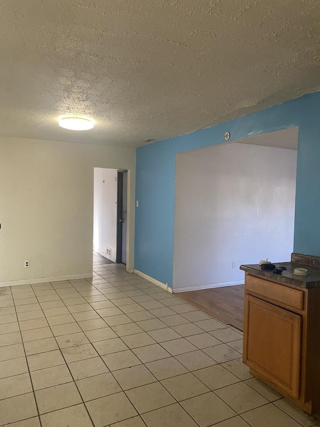 unfurnished room with light tile patterned floors and a textured ceiling