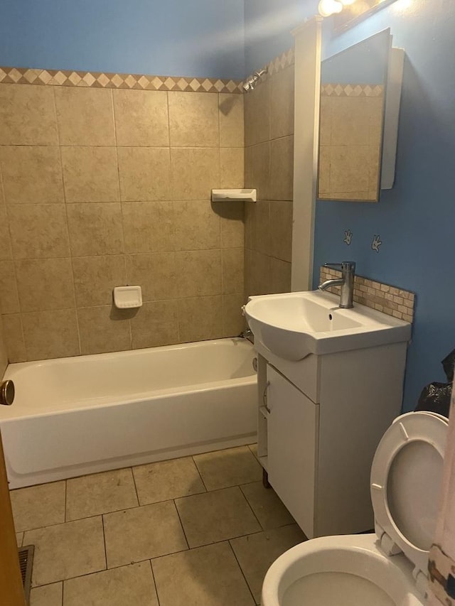 full bathroom featuring tile patterned flooring, tiled shower / bath combo, toilet, and vanity