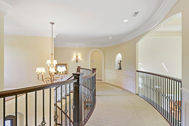 corridor with crown molding, an inviting chandelier, and light carpet