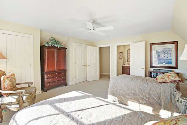 bedroom featuring ensuite bathroom, vaulted ceiling, light colored carpet, and ceiling fan