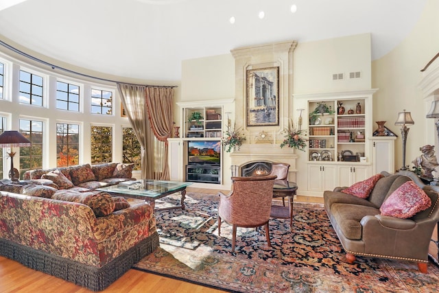 living room featuring a fireplace, light hardwood / wood-style floors, and a high ceiling