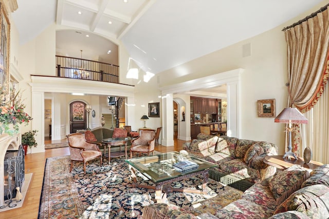 living room featuring beam ceiling, a towering ceiling, and light hardwood / wood-style floors