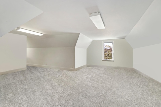 additional living space featuring light carpet and vaulted ceiling