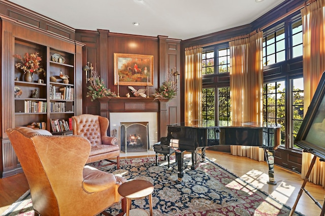 sitting room featuring built in shelves, wood walls, and light wood-type flooring