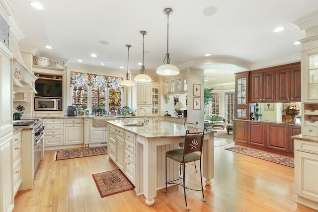 kitchen with a breakfast bar, crown molding, hanging light fixtures, stainless steel appliances, and a kitchen island with sink