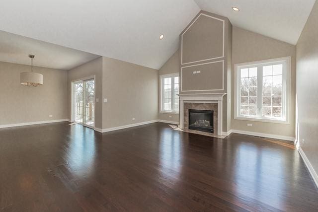 unfurnished living room with vaulted ceiling, dark wood-type flooring, and a wealth of natural light