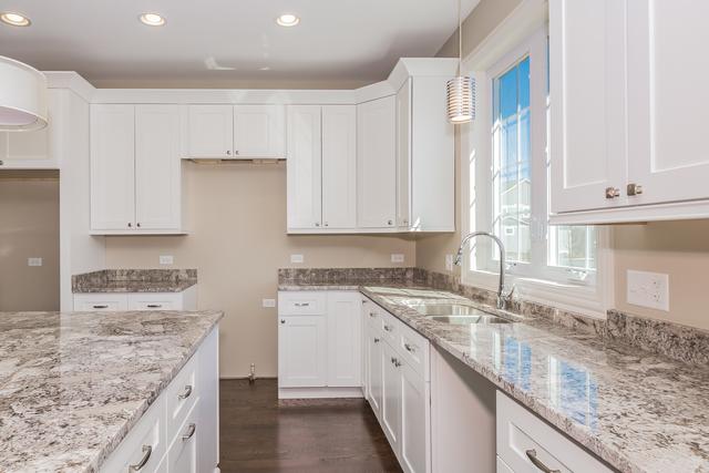 kitchen with dark hardwood / wood-style floors, decorative light fixtures, white cabinetry, sink, and light stone countertops