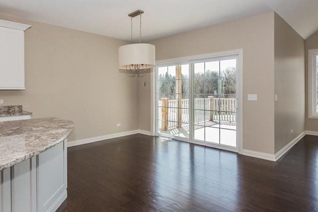 unfurnished dining area with dark wood-type flooring and vaulted ceiling