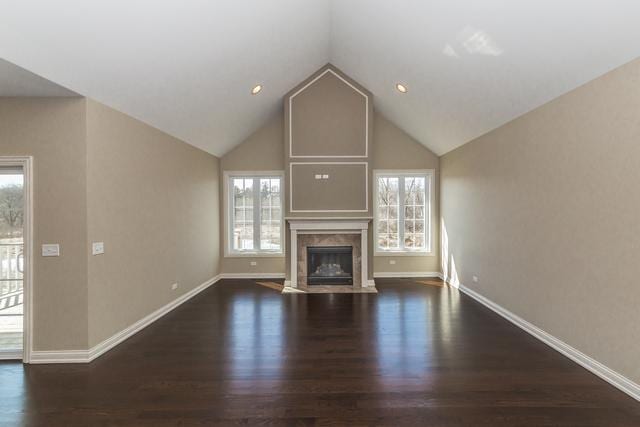 unfurnished living room with a premium fireplace, vaulted ceiling, and dark hardwood / wood-style floors