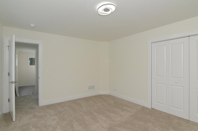 unfurnished bedroom featuring light colored carpet and a closet