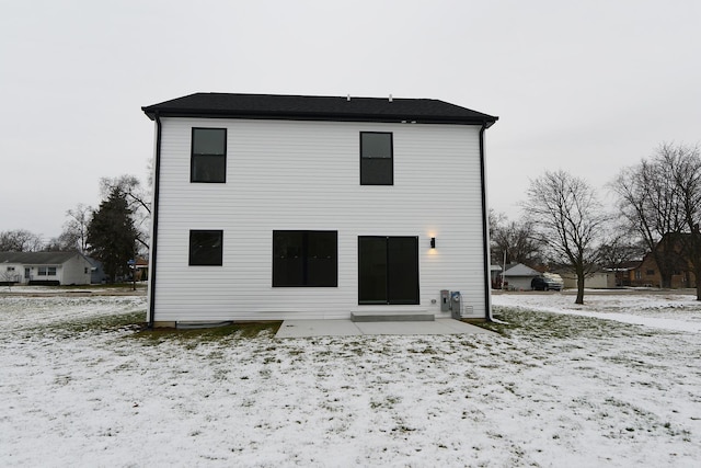 snow covered back of property with a patio area