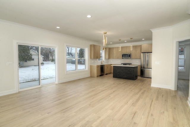 kitchen with a center island, sink, light wood-type flooring, decorative light fixtures, and stainless steel appliances