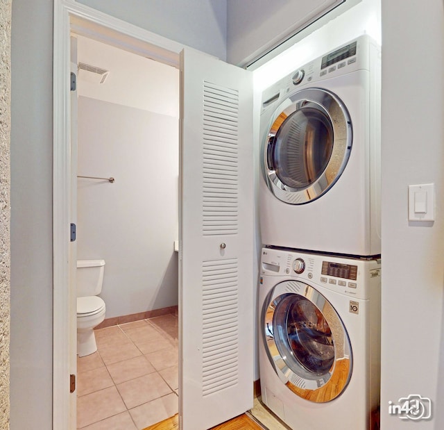 laundry room featuring light tile patterned floors and stacked washing maching and dryer