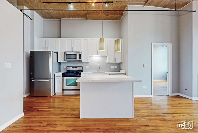 kitchen with appliances with stainless steel finishes, wood ceiling, white cabinetry, a high ceiling, and light hardwood / wood-style flooring