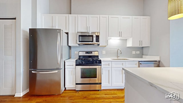 kitchen with appliances with stainless steel finishes, white cabinetry, and light hardwood / wood-style flooring