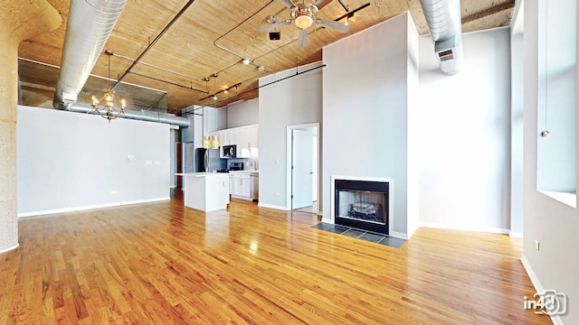 unfurnished living room with a towering ceiling, ceiling fan, hardwood / wood-style floors, and sink