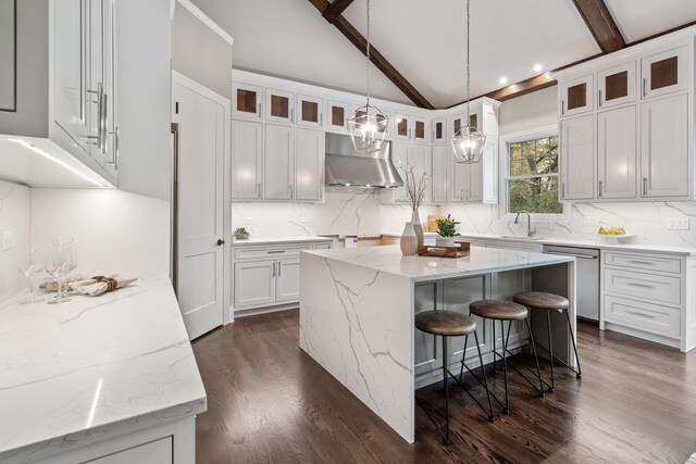 kitchen featuring beamed ceiling, dark wood-type flooring, wall chimney exhaust hood, stainless steel dishwasher, and hanging light fixtures