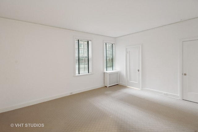 unfurnished room featuring radiator heating unit and light colored carpet